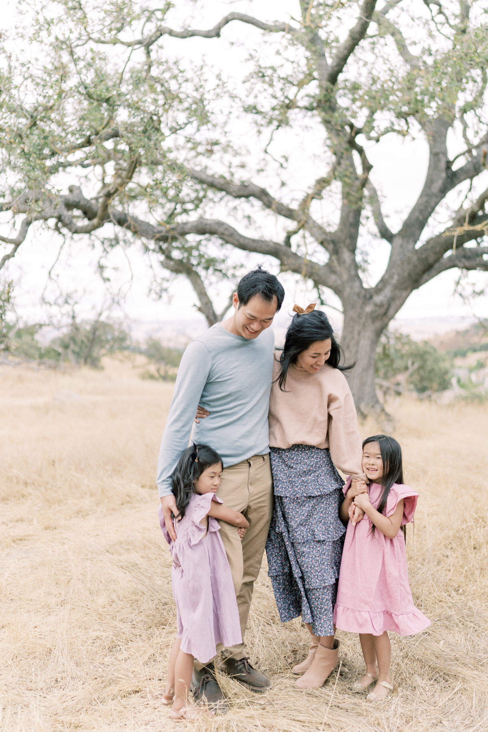 Family of four looking at each other on a grassy hill